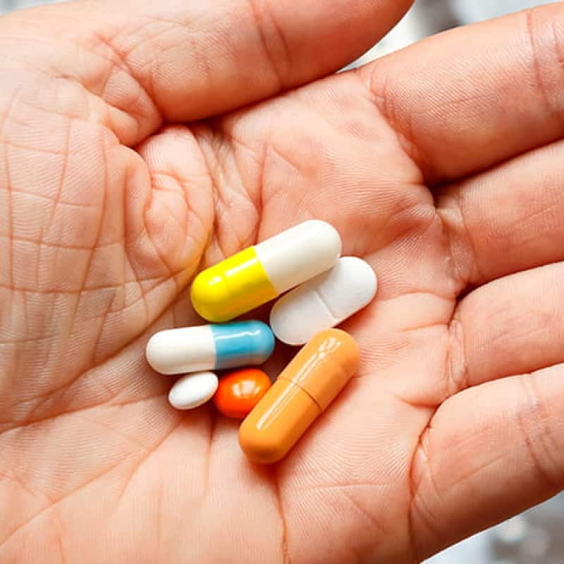 Hand holding multicoloured tablets, e-Surgery's campaign against counterfeit medication