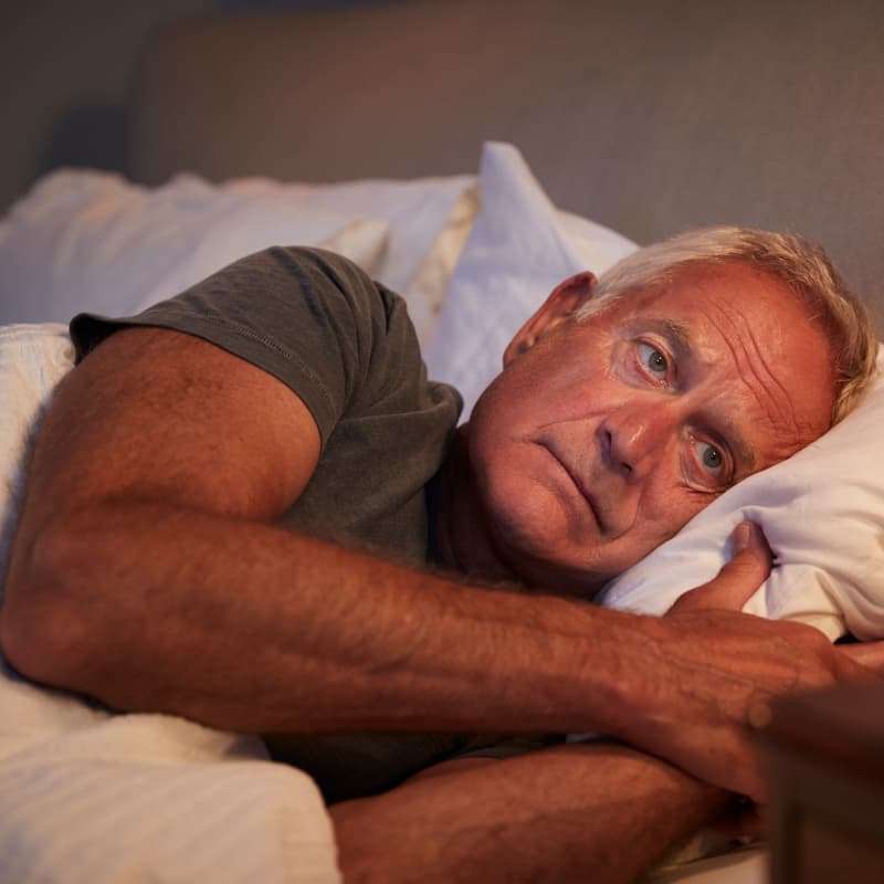 man in bed suffering from male menopause | e-surgery