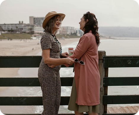 Two women having conversation on a bridge with a view to the city
